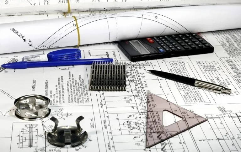 Plans techniques, équerre et pièces mécaniques sur un bureau
